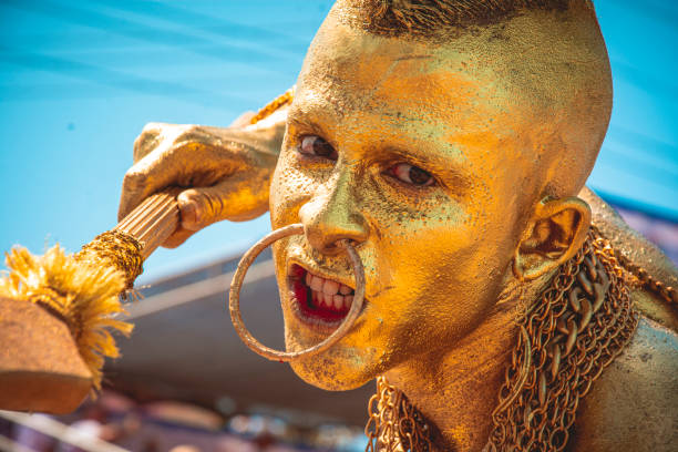 Carnaval de Barranquilla (Colombia) 2023, 02-18-2023, A man in the traditional Barranquilla carnival costume, Traditional costume of the carnival of barranquilla, Indian golden mohican.
Man disguised as a Mohican Indian warrior making a defiant face with his body painted in gold, alluding to the legend of El Dorado.