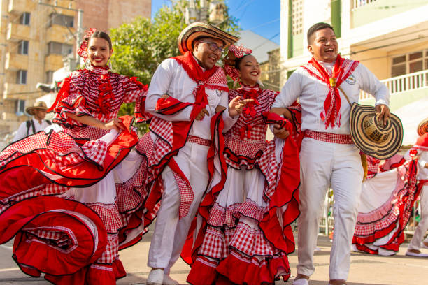 A group of cumbia dancers dance with their arms intertwined, shouting with joy as they celebrate the Barranquilla's Carnival