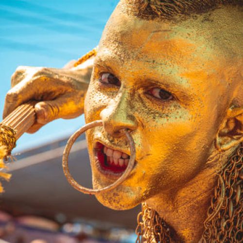 Carnaval de Barranquilla (Colombia) 2023, 02-18-2023, A man in the traditional Barranquilla carnival costume, Traditional costume of the carnival of barranquilla, Indian golden mohican.
Man disguised as a Mohican Indian warrior making a defiant face with his body painted in gold, alluding to the legend of El Dorado.